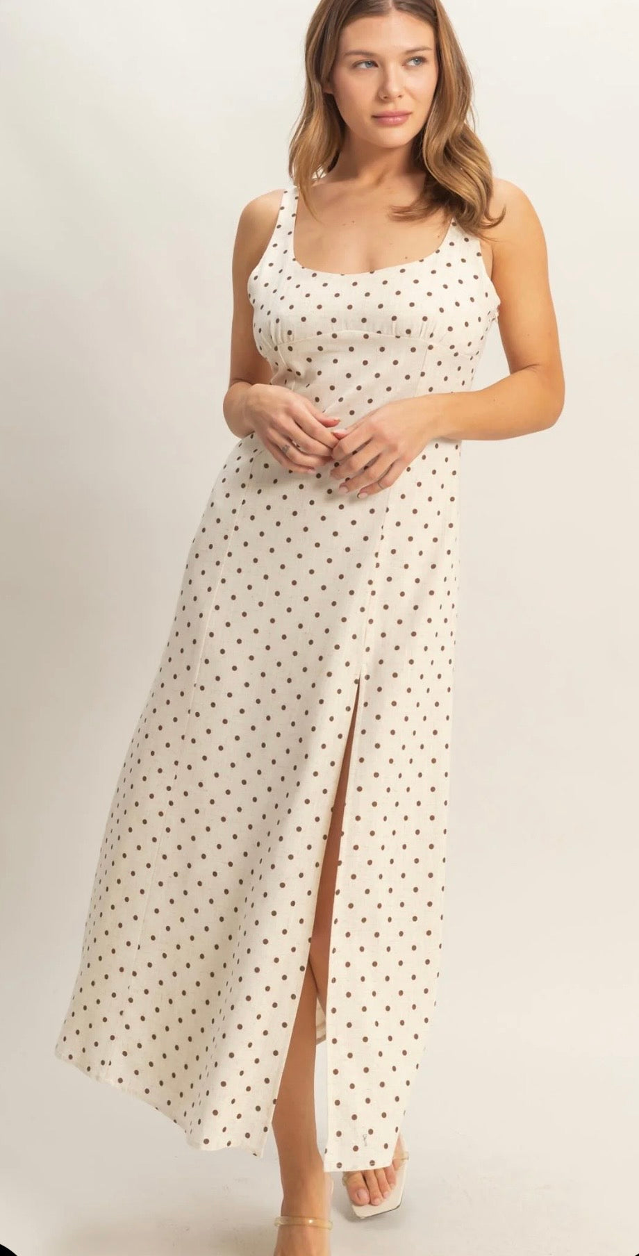 Woman wearing a white dress with red polka dots on a plain background